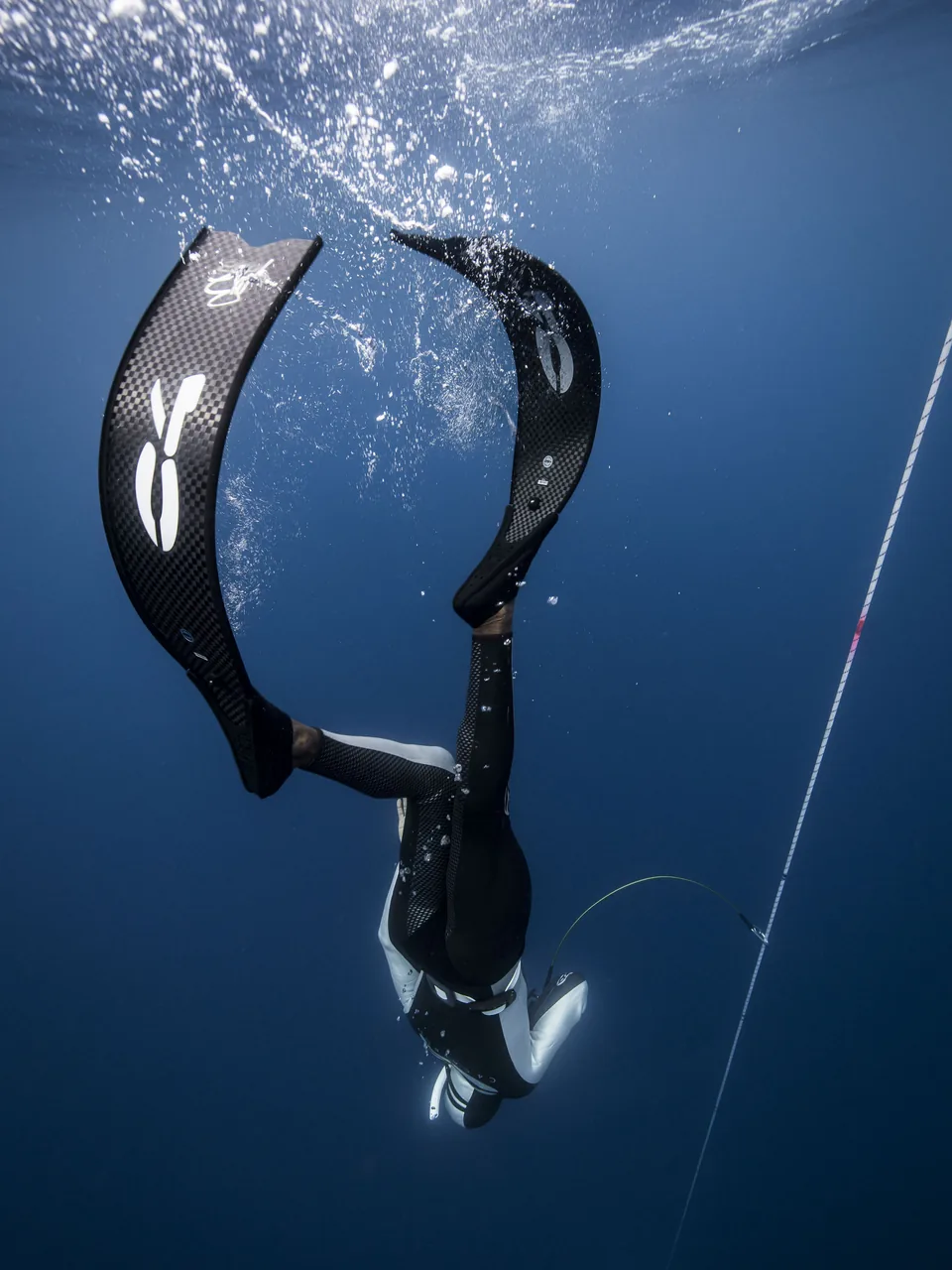 Freediver descending along the line in deep blue water, Karukera Free-Dive