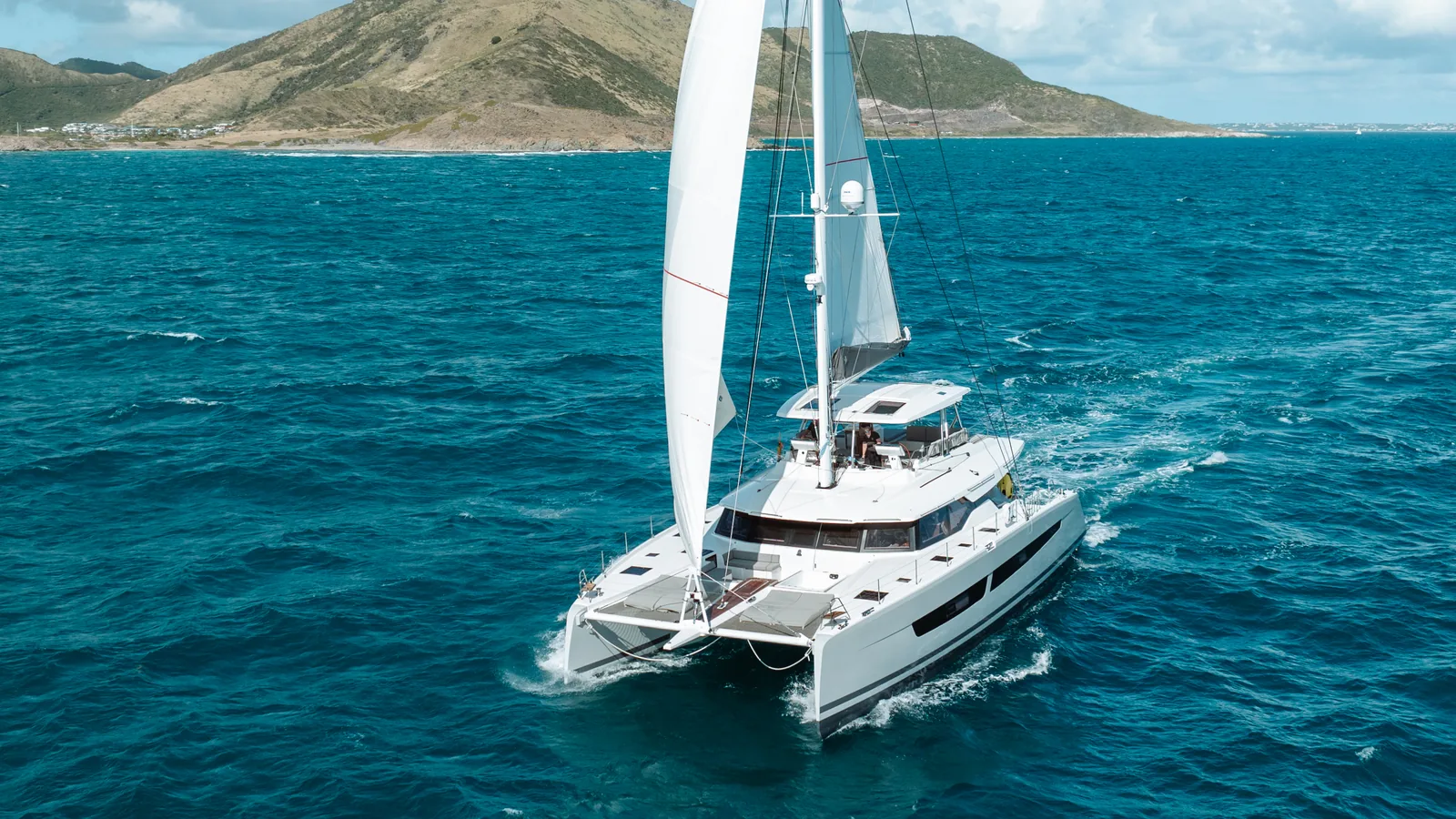 Crewed sailing catamaran under sail off a Caribbean island