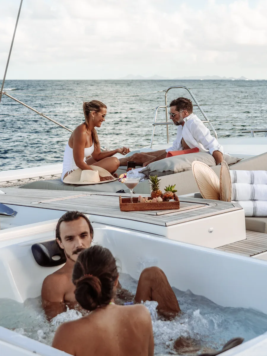 Guests relaxing on a catamaran foredeck and in the deck jacuzzi